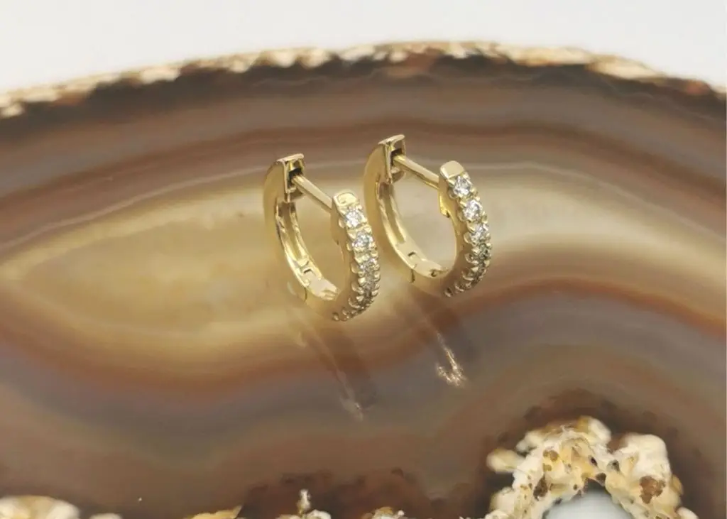 A-pair-of-petite-9KT-yellow-gold-diamond-huggies-on-natural-stone-display-stand
