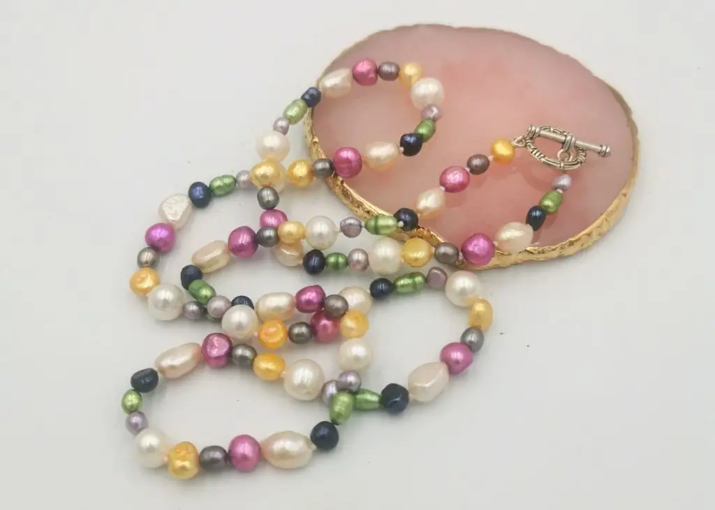 A-multicoloured-pearl-necklace-lying-on-a-flat-pink-stone-display-stand